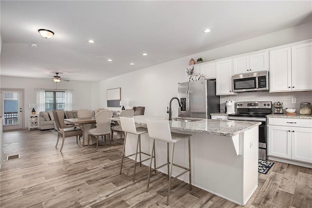 kitchen featuring visible vents, backsplash, appliances with stainless steel finishes, light wood-style floors, and white cabinets