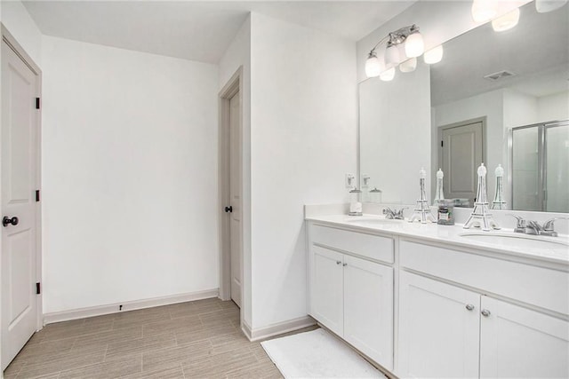 bathroom featuring a stall shower, visible vents, a sink, and double vanity