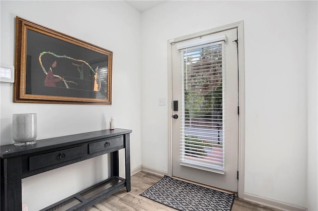 doorway with a wealth of natural light, light wood-style flooring, and baseboards