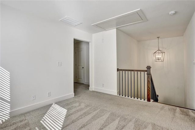 carpeted empty room with attic access, visible vents, and baseboards