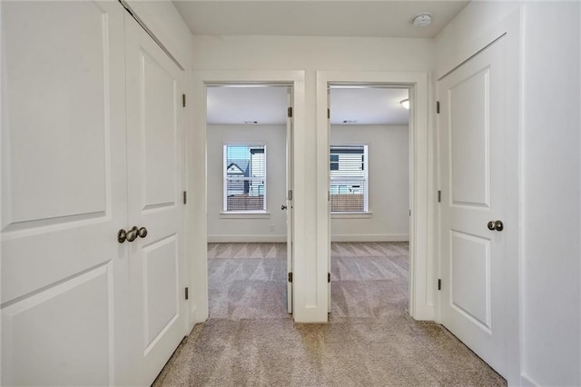 corridor with light carpet and baseboards