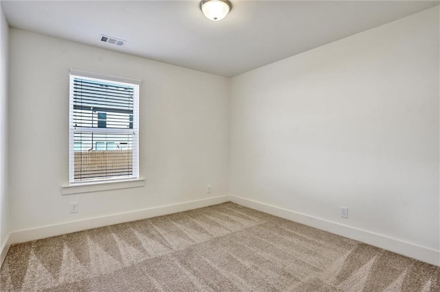 empty room with carpet floors, visible vents, and baseboards