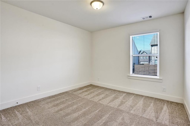 spare room with carpet flooring, visible vents, and baseboards