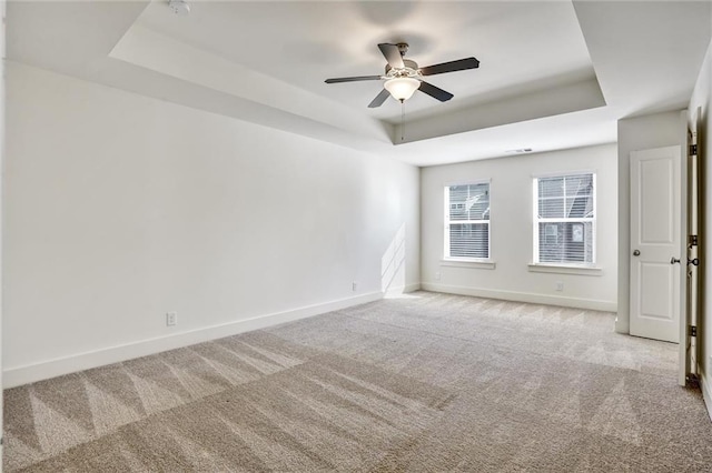 spare room featuring ceiling fan, carpet, baseboards, and a raised ceiling