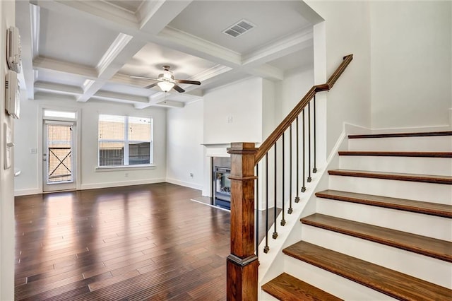 stairway featuring beam ceiling, visible vents, a glass covered fireplace, wood finished floors, and baseboards