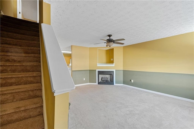 3127 Fields Dr, Lithonia, GA 30038 - unfurnished living room featuring a textured ceiling, carpet flooring, a ceiling fan, stairs, and a fireplace