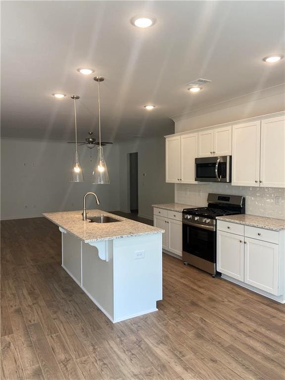 kitchen with a kitchen island with sink, sink, white cabinets, appliances with stainless steel finishes, and hardwood / wood-style floors