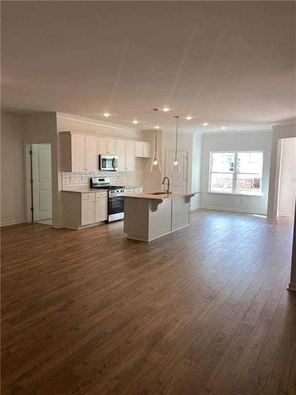 kitchen with pendant lighting, dark wood-type flooring, an island with sink, white cabinetry, and stainless steel appliances