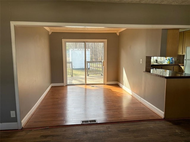 interior space featuring visible vents, a sink, baseboards, and wood finished floors