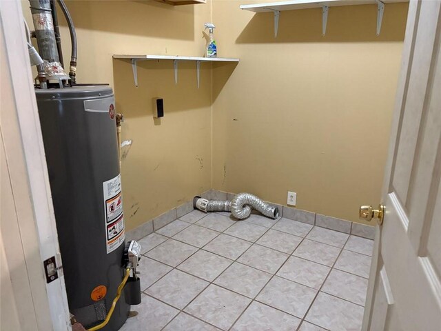 clothes washing area featuring laundry area, water heater, and light tile patterned floors