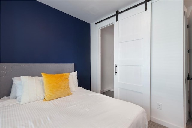 bedroom with baseboards and a barn door