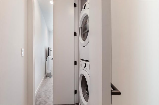 laundry area featuring baseboards, laundry area, and stacked washer / dryer