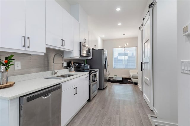 kitchen featuring white cabinets, appliances with stainless steel finishes, a sink, and tasteful backsplash