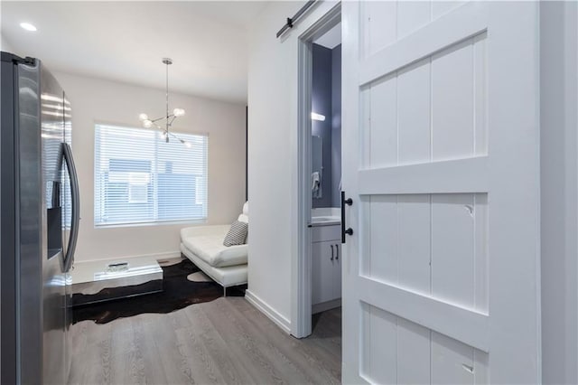interior space featuring a barn door, wood finished floors, baseboards, a chandelier, and recessed lighting