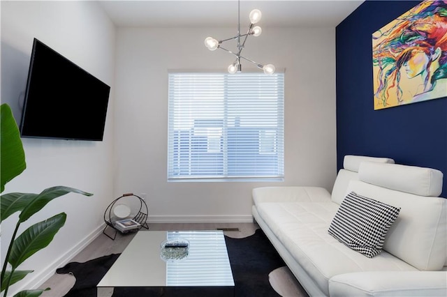sitting room featuring baseboards, a chandelier, a healthy amount of sunlight, and wood finished floors