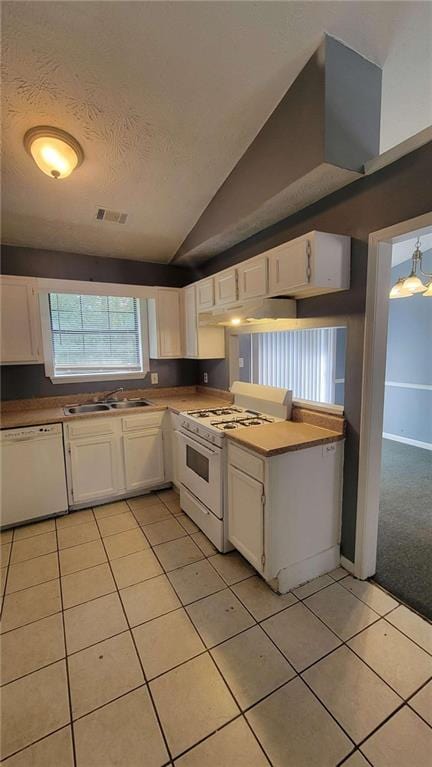 kitchen featuring light tile patterned floors, white cabinets, vaulted ceiling, and white appliances