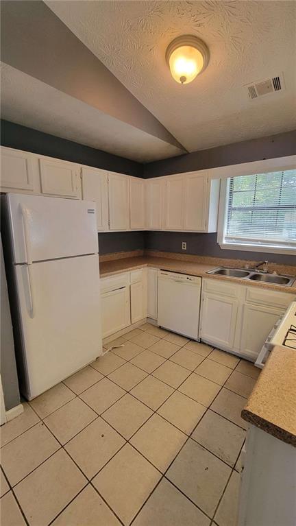 kitchen featuring white cabinetry, light tile patterned flooring, white appliances, a textured ceiling, and sink