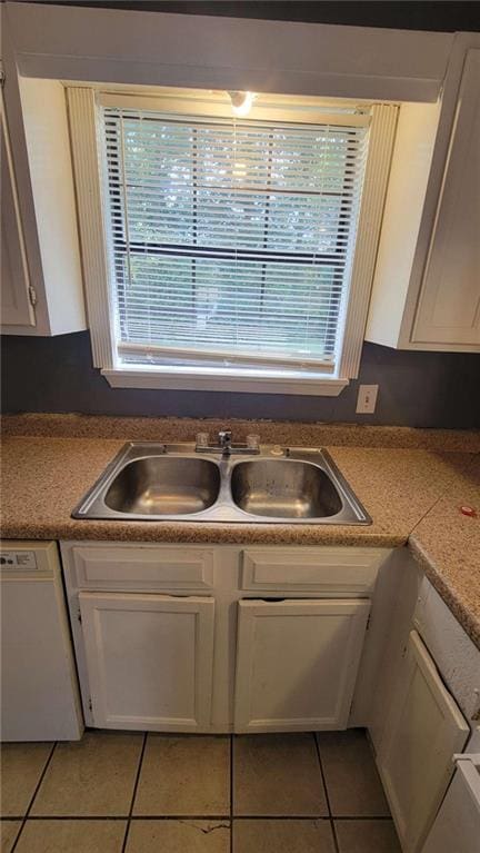 kitchen featuring sink, light tile patterned floors, white cabinetry, and white dishwasher