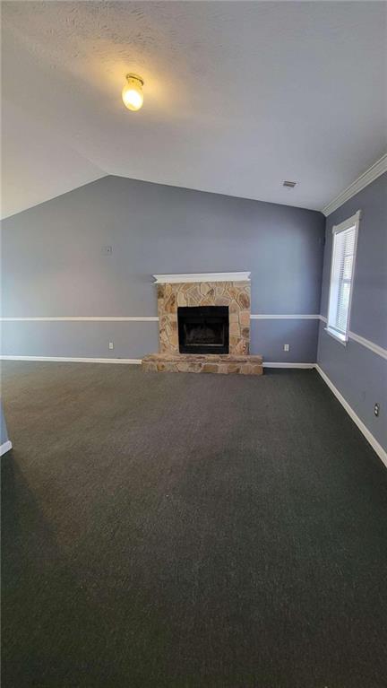 unfurnished living room with crown molding, a fireplace, carpet flooring, and lofted ceiling