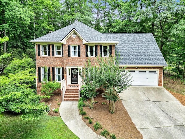135 Crimson Rdg, Tyrone, GA 30290 - colonial-style house with driveway, brick siding, roof with shingles, a garage, and view of wooded area
