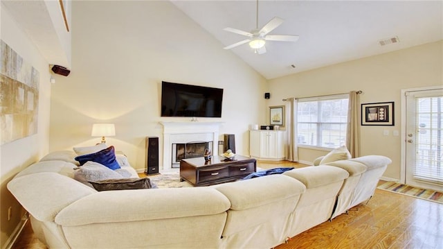 living room featuring ceiling fan, high vaulted ceiling, a wealth of natural light, and light wood-type flooring