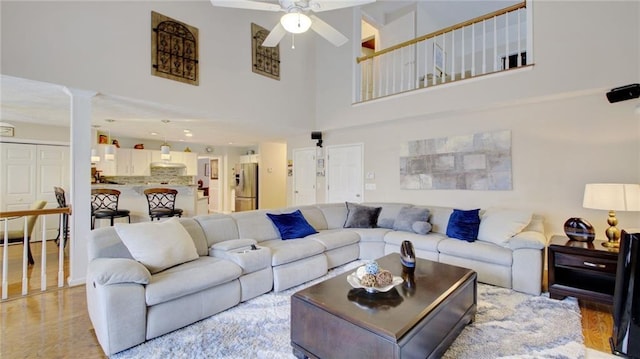 living room with a towering ceiling, decorative columns, and ceiling fan