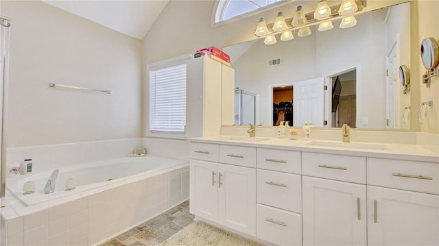 bathroom with a relaxing tiled tub, lofted ceiling, vanity, and a wealth of natural light