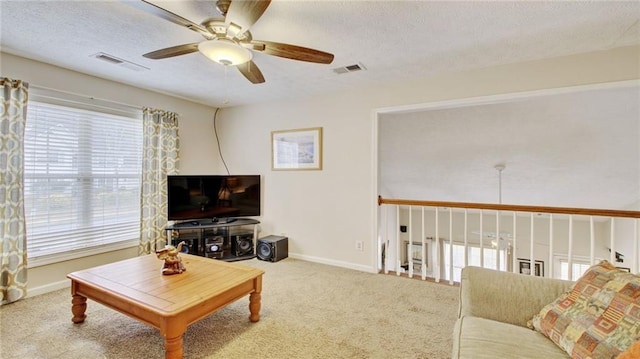 carpeted living room with ceiling fan, a textured ceiling, and a wealth of natural light