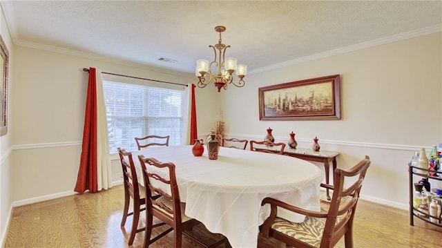 dining space featuring ornamental molding, a textured ceiling, an inviting chandelier, and light hardwood / wood-style flooring