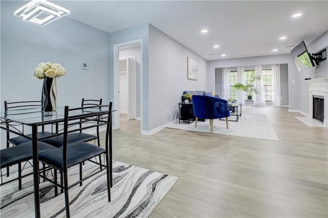 dining room with a high end fireplace and light wood-type flooring