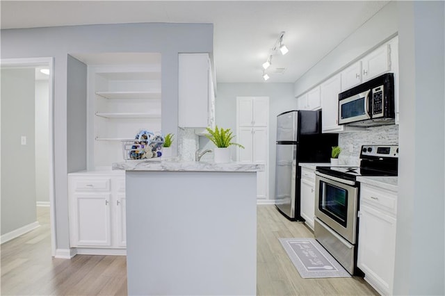 kitchen with stainless steel appliances, white cabinetry, tasteful backsplash, and light hardwood / wood-style floors