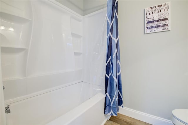 bathroom featuring hardwood / wood-style flooring, shower / tub combo with curtain, and toilet