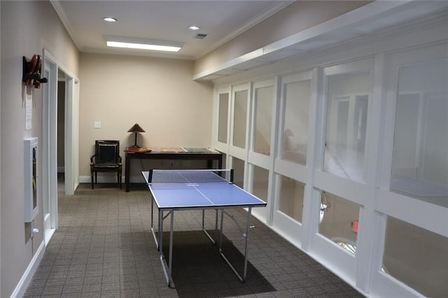 rec room with dark colored carpet and ornamental molding