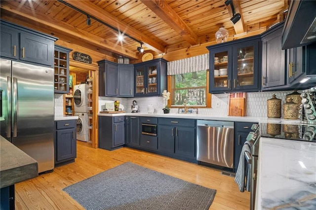 kitchen with built in appliances, stacked washing maching and dryer, wooden ceiling, tasteful backsplash, and light wood finished floors