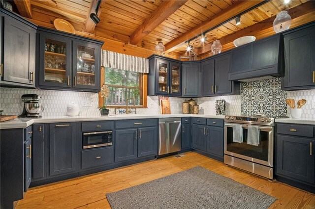 bar with track lighting, a sink, stainless steel appliances, wooden ceiling, and custom exhaust hood