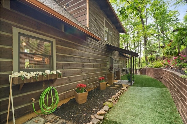 view of side of home with a lawn, roof with shingles, and fence