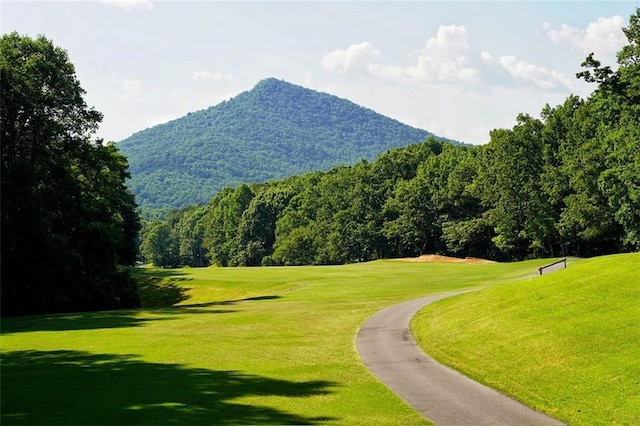 view of community featuring a lawn, a mountain view, and view of golf course