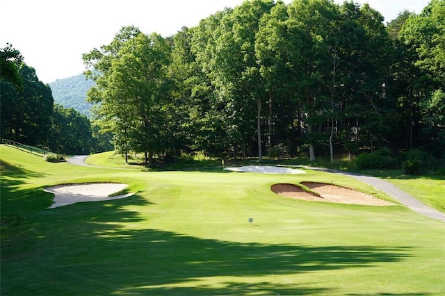 surrounding community with view of golf course and a yard