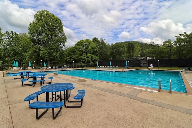 community pool with a patio area and fence