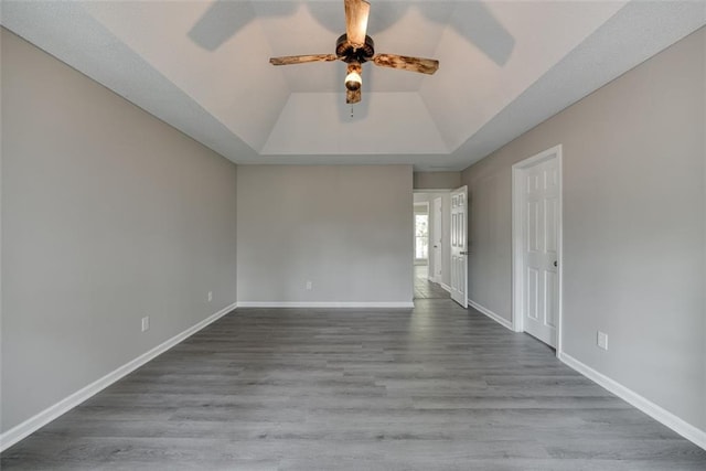 spare room featuring a tray ceiling, ceiling fan, hardwood / wood-style floors, and vaulted ceiling