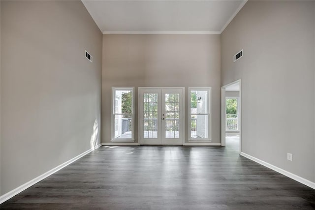 spare room with a high ceiling, crown molding, french doors, and dark wood-type flooring