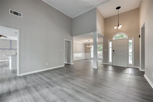 foyer entrance featuring hardwood / wood-style floors, ceiling fan with notable chandelier, a high ceiling, and ornamental molding