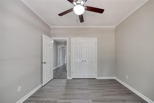 unfurnished bedroom with ceiling fan, a closet, crown molding, and light hardwood / wood-style flooring