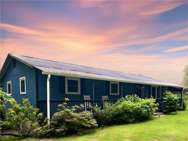 back of house at dusk featuring a yard and metal roof