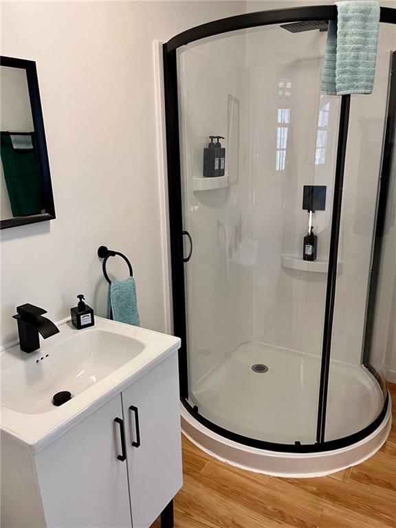 bathroom with a stall shower and wood finished floors