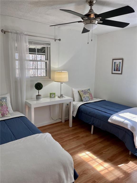 bedroom featuring light wood-style flooring, a textured ceiling, and a ceiling fan