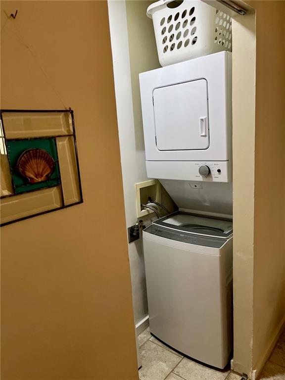 washroom with stacked washer / drying machine and baseboards