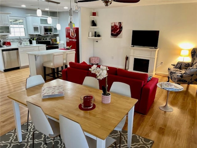 dining area featuring light wood-type flooring, recessed lighting, a fireplace, and ceiling fan