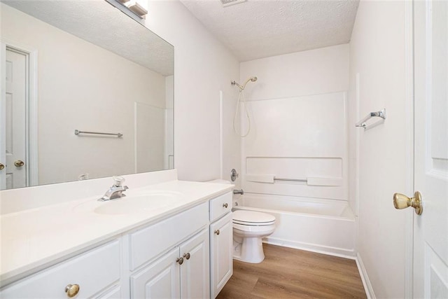 full bath featuring tub / shower combination, toilet, vanity, wood finished floors, and a textured ceiling