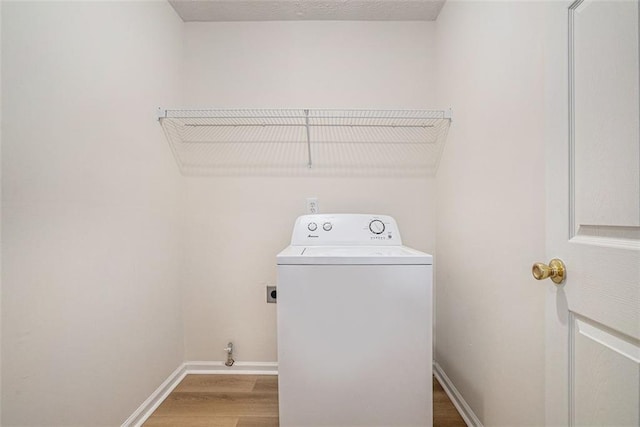 clothes washing area with a textured ceiling, wood finished floors, baseboards, washer / dryer, and laundry area